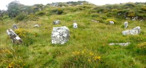 A stone circle set in grass on a hillside in Ireland.